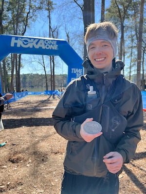 The author holding up a Rocky Raccoon 100-Mile ultra-marathon finisher medal